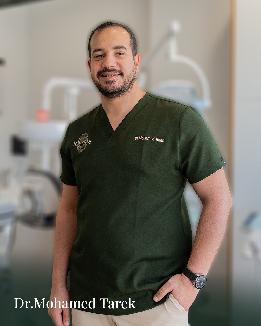 Portrait of Dr. Mohamed Tarek in green Identia scrubs against a soft clinic background.