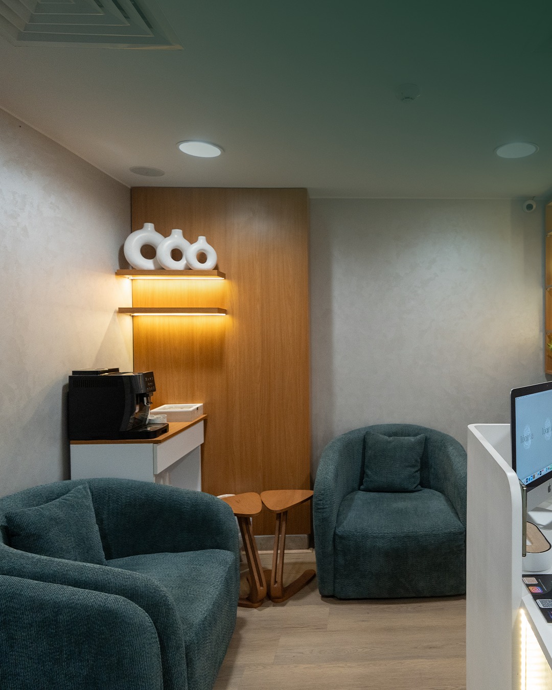Lounge with deep teal armchairs and warm walnut feature wall.