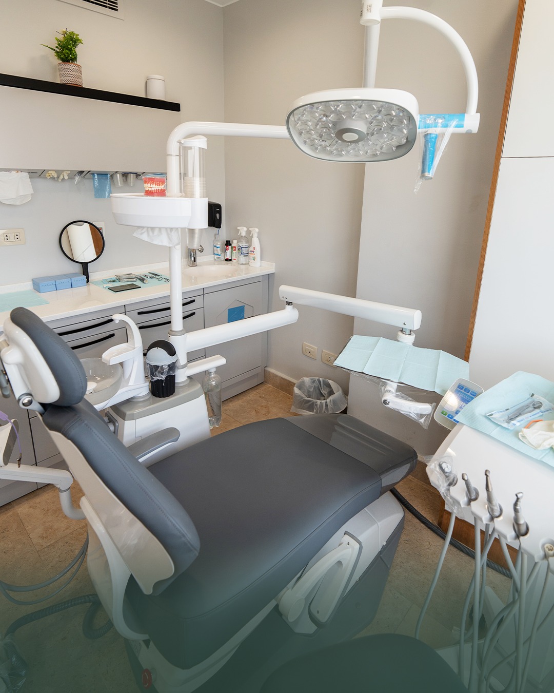 Treatment room with sage cabinetry and the dental chair under soft daylight.